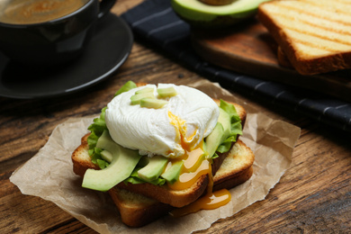 Photo of Delicious poached egg sandwich served on wooden table