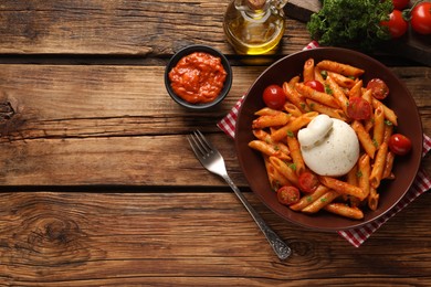 Photo of Delicious pasta with burrata cheese and tomatoes served on wooden table, flat lay. Space for text