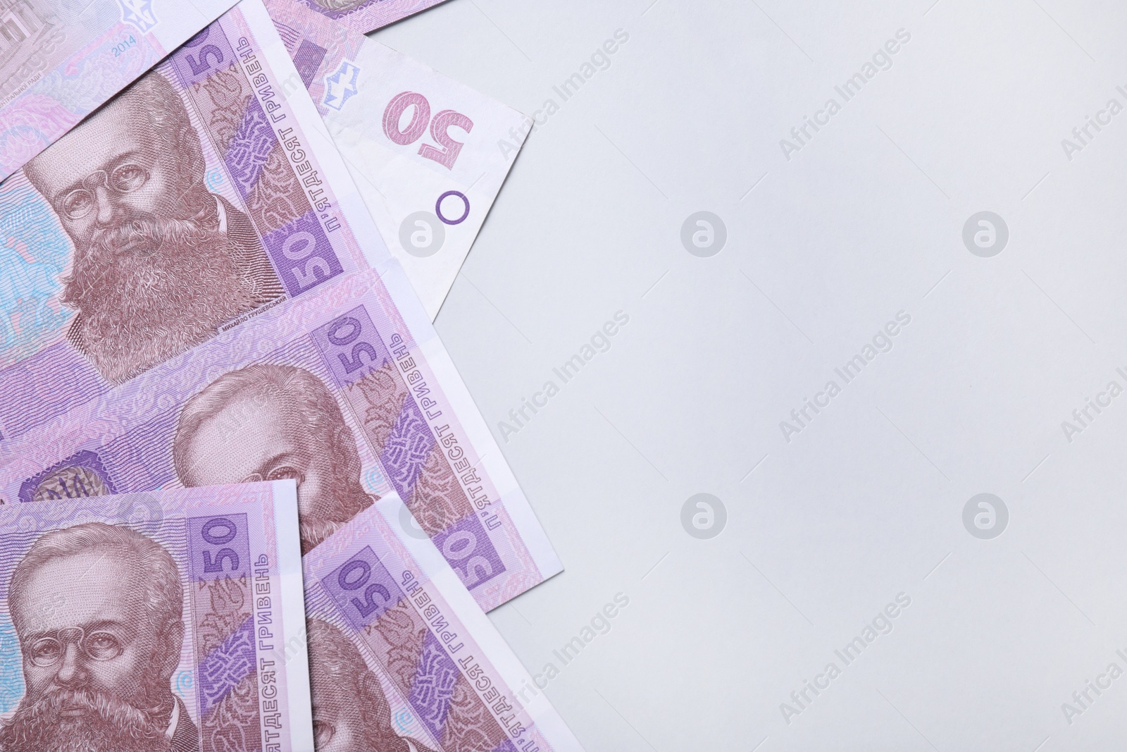 Photo of Ukrainian money on light grey background, flat lay. Space for text