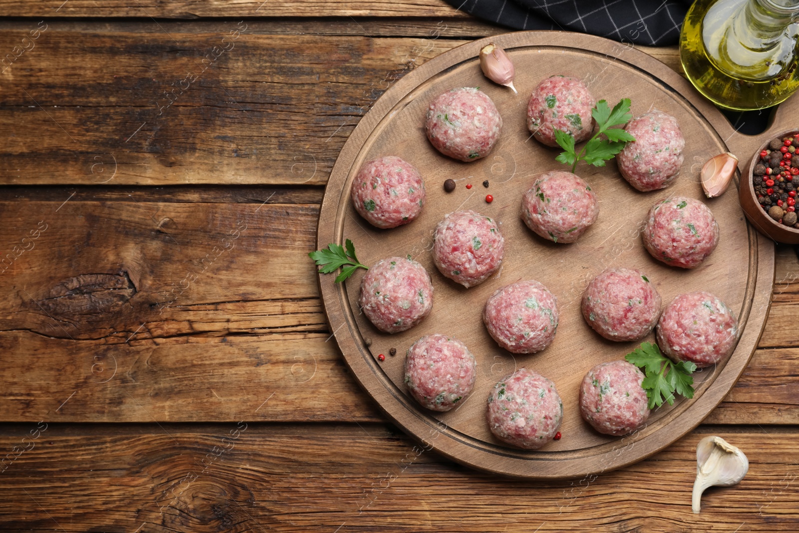 Photo of Many fresh raw meatballs and ingredients on wooden table, flat lay. Space for text