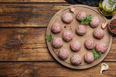 Many fresh raw meatballs and ingredients on wooden table, flat lay. Space for text