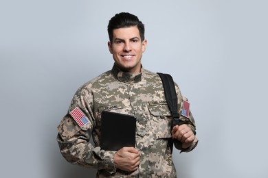 Cadet with backpack and tablet on light grey background. Military education