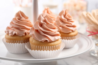 Photo of Stand with tasty cupcakes on table, closeup. Candy bar