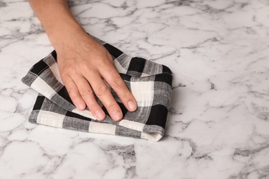 Woman wiping marble table with kitchen towel, closeup