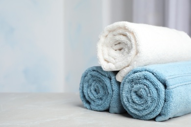 Photo of Rolled bath towels on table against blurred background. Space for text