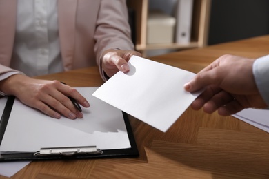 Employee giving resignation letter to boss in office, closeup