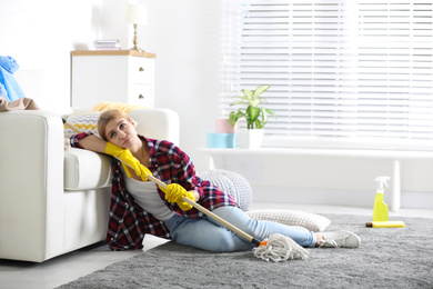 Photo of Lazy young woman with mop at home. Cleaning and housework