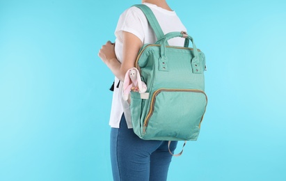 Photo of Woman with maternity backpack for baby accessories on color background, closeup