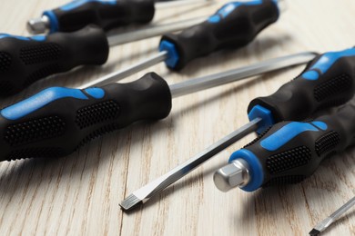 Photo of Set of screwdrivers on white wooden table, closeup