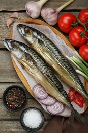 Photo of Delicious smoked mackerels and spices on wooden table, flat lay