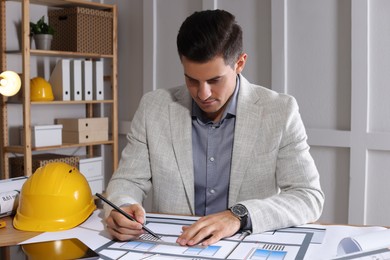 Photo of Architect working with construction drawings in office