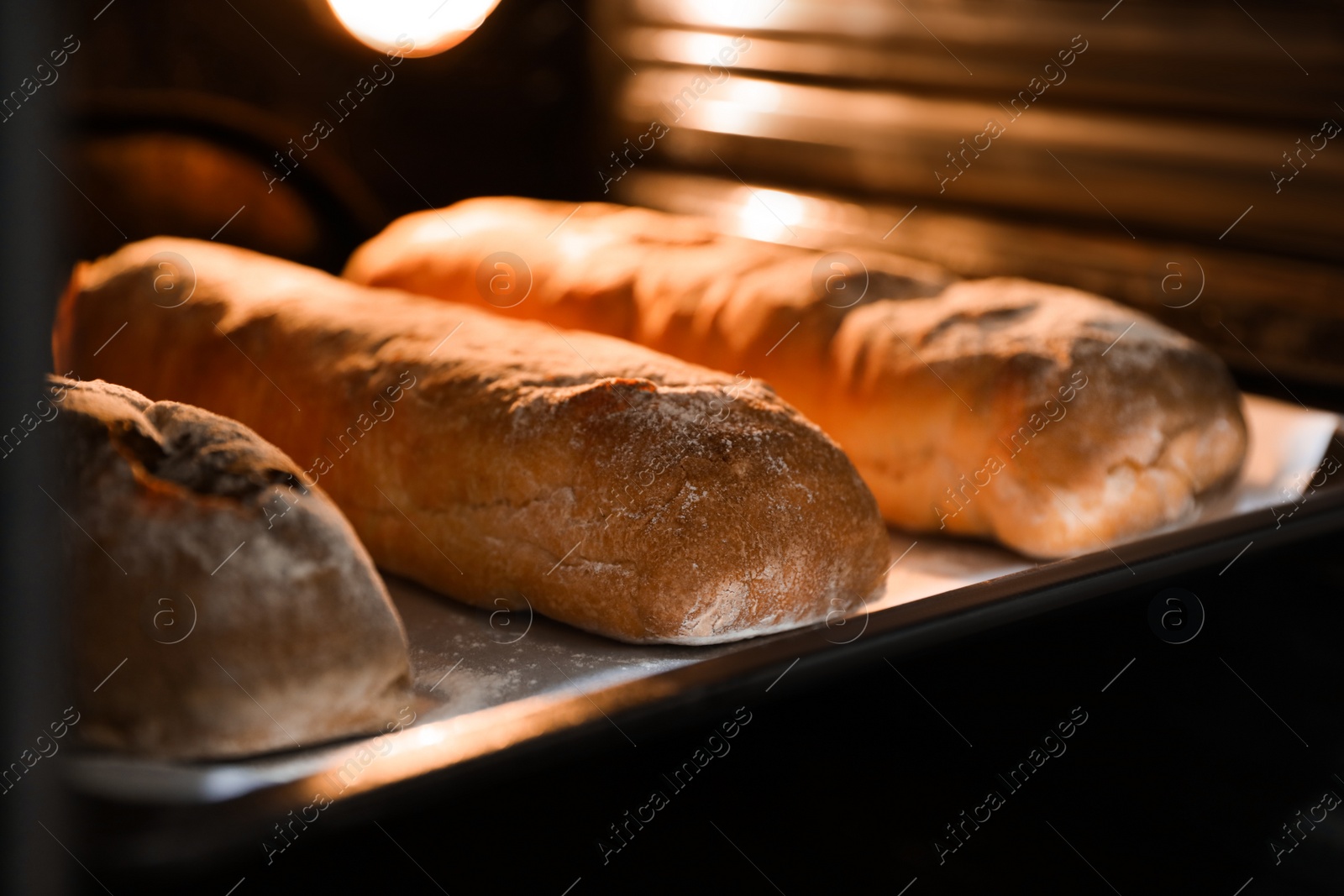 Photo of Cooking fresh crispy ciabattas in oven, closeup