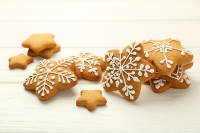 Tasty Christmas cookies with icing on white wooden table