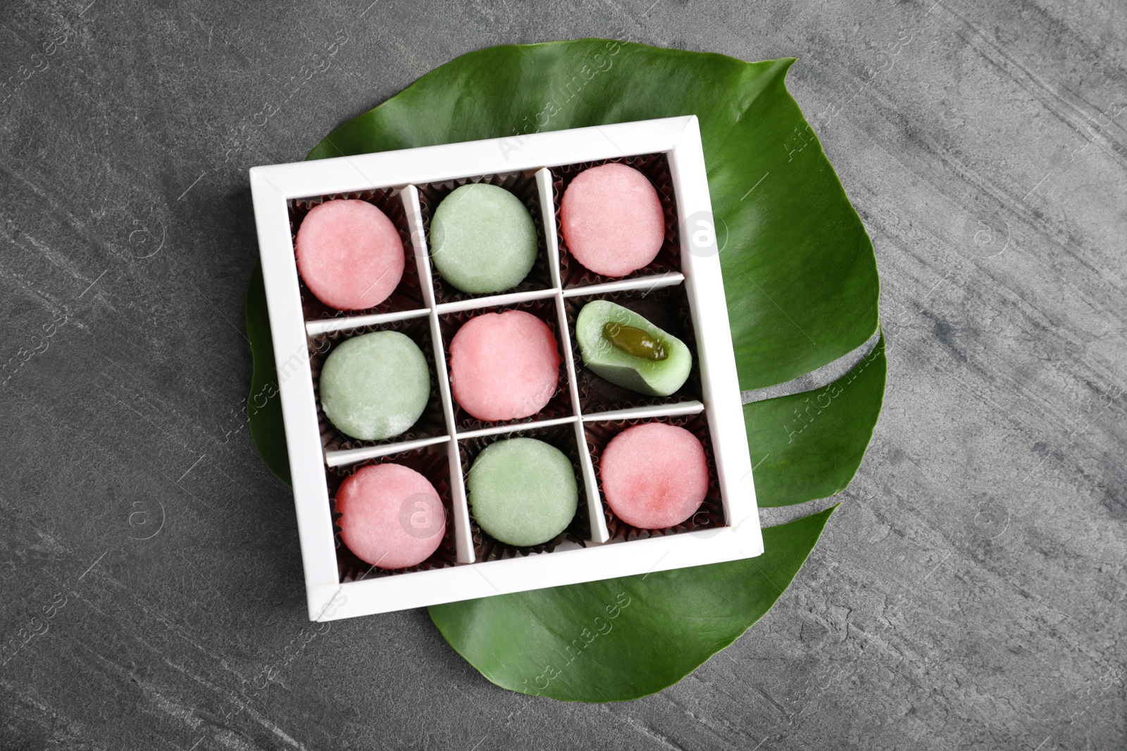 Photo of Box with different delicious mochi on grey table, top view