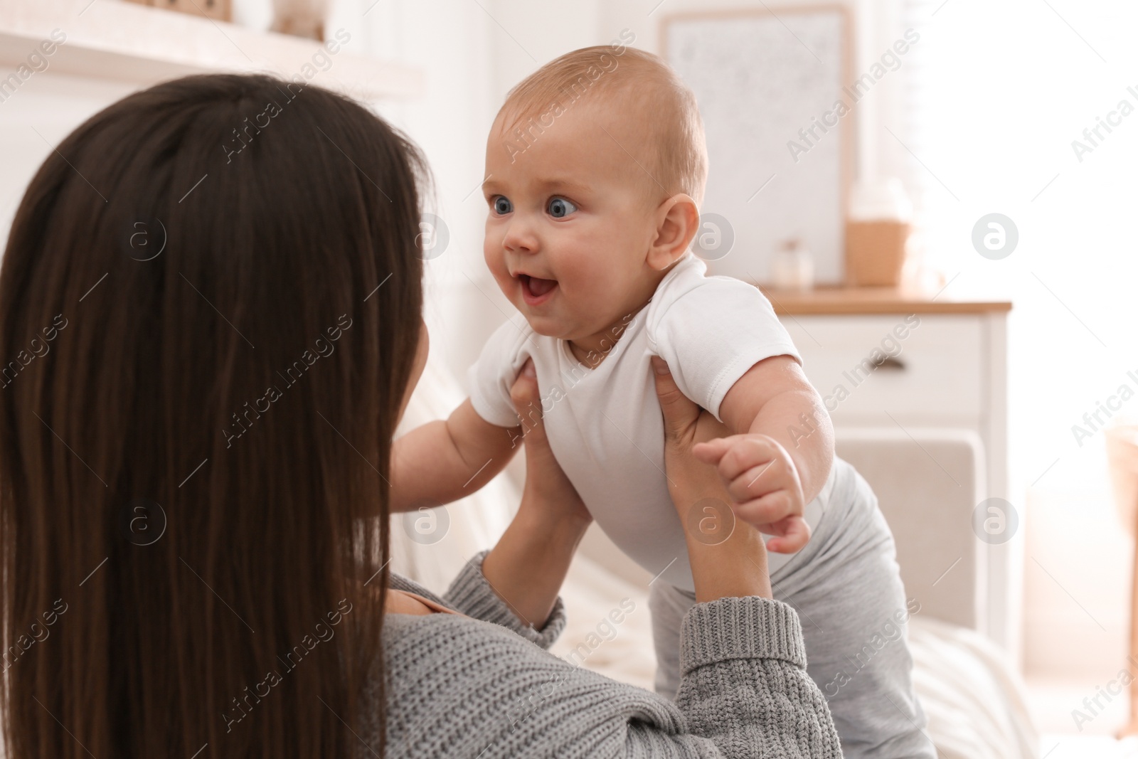 Photo of Happy young mother with her cute baby in living room