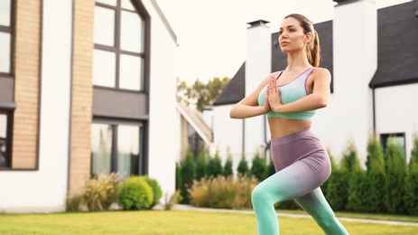 Woman practicing morning yoga at backyard. Healthy lifestyle