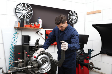 Photo of Man working with car disk lathe machine at tire service