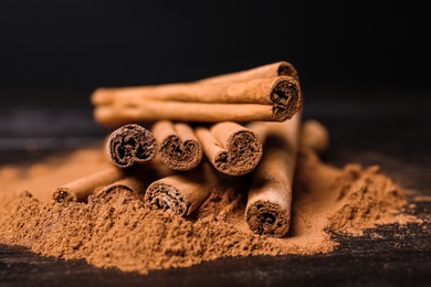 Photo of Aromatic cinnamon sticks and powder on table, closeup