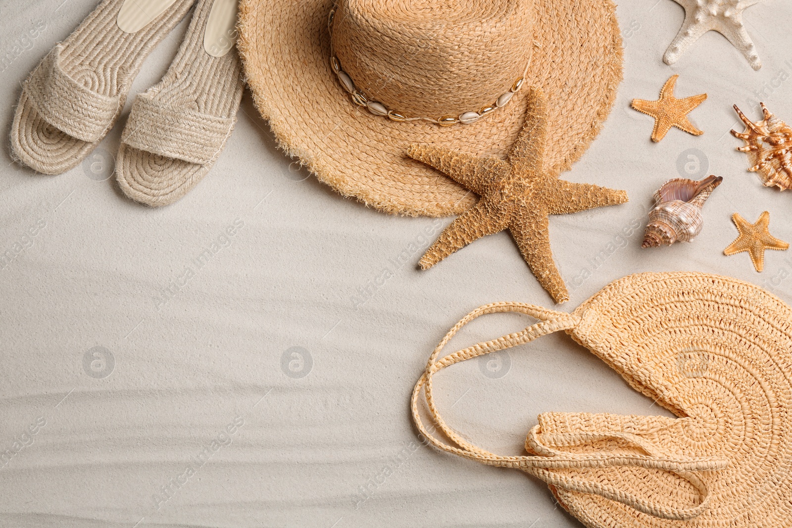 Photo of Different beach accessories on sand, flat lay. Space for text