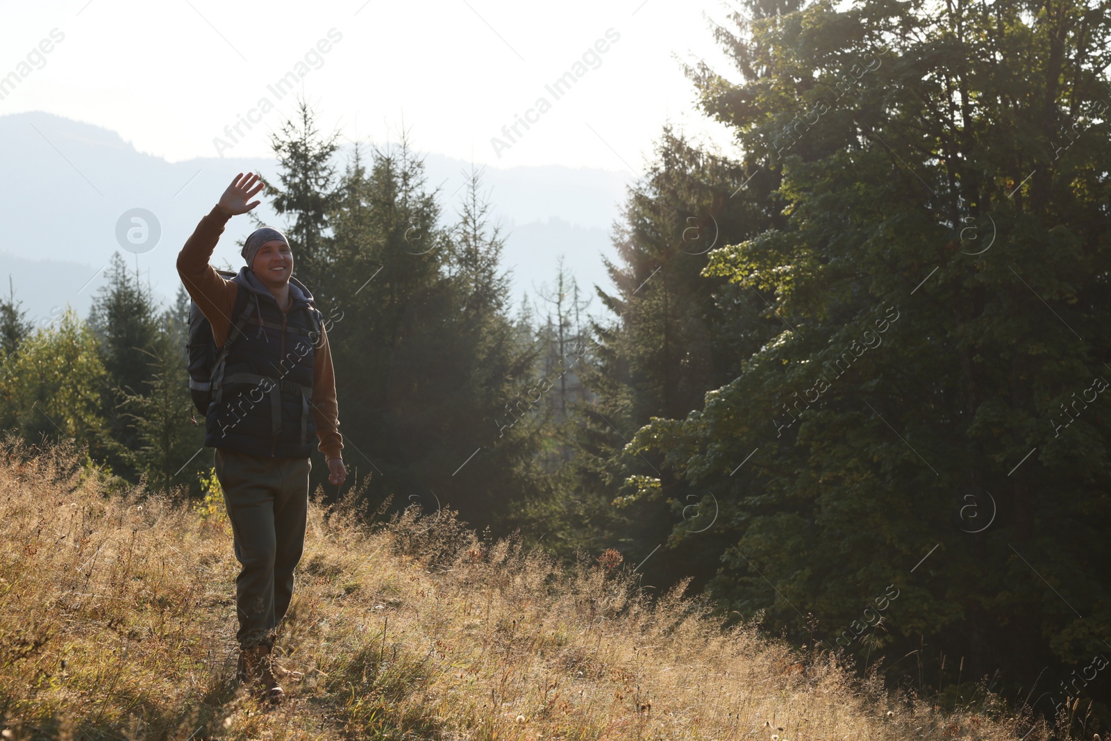 Photo of Tourist with backpack in mountains on sunny day. Space for text