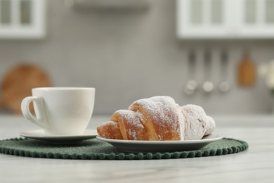 Photo of Croissant and cup of hot drink on white table in kitchen, space for text