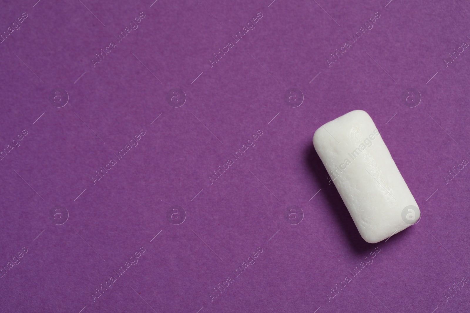 Photo of Tasty white chewing gum on purple background, top view. Space for text