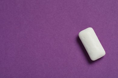 Photo of Tasty white chewing gum on purple background, top view. Space for text