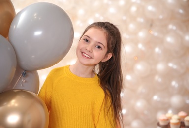 Happy little girl with balloons in beautifully decorated room at home. Birthday celebration