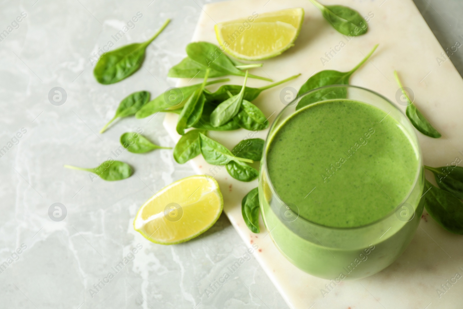 Photo of Glass of healthy green smoothie with fresh spinach on light table, above view