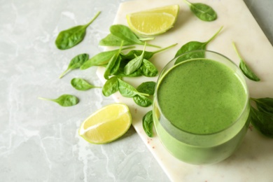 Photo of Glass of healthy green smoothie with fresh spinach on light table, above view