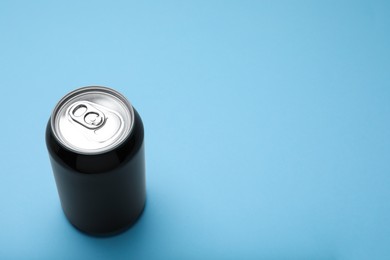Photo of Black can of energy drink on light blue background. Space for text