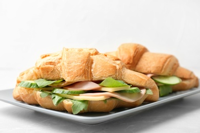 Photo of Tasty croissant sandwiches with sausage on plate, closeup