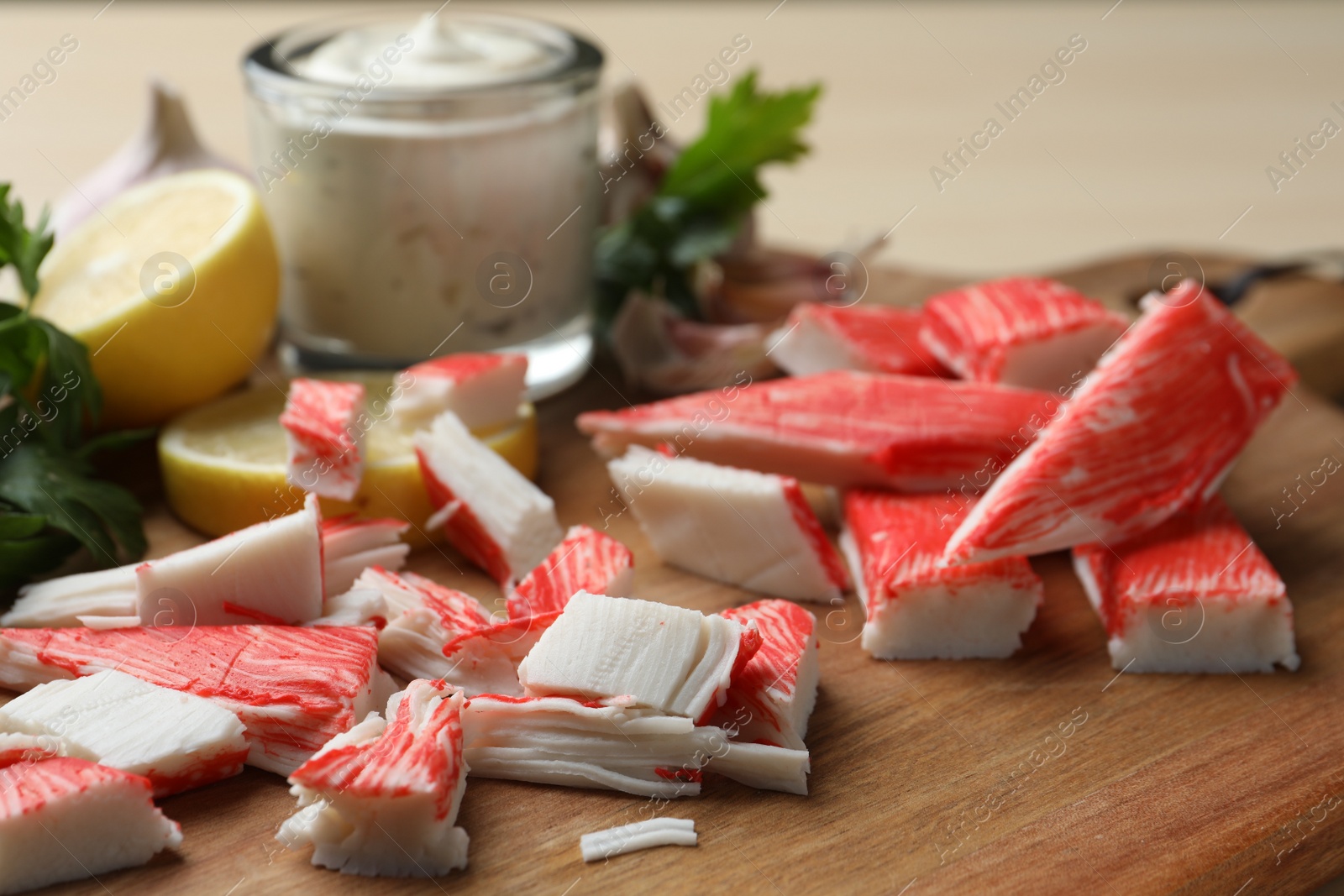 Photo of Delicious crab sticks on wooden board, closeup