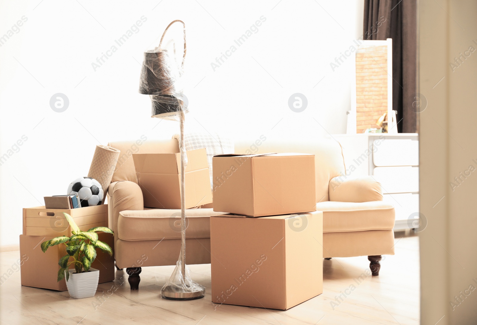 Photo of Cardboard boxes and household stuff in living room. Moving day