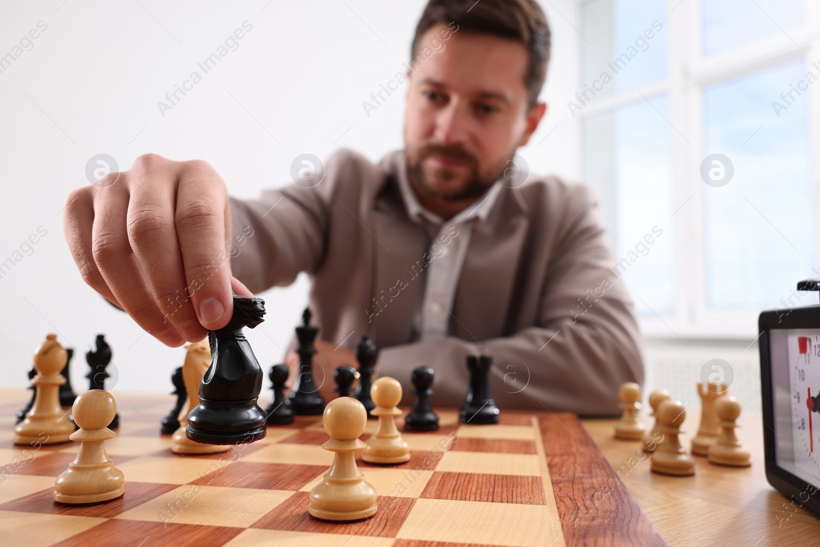 Photo of Man playing chess during tournament at table indoors, selective focus