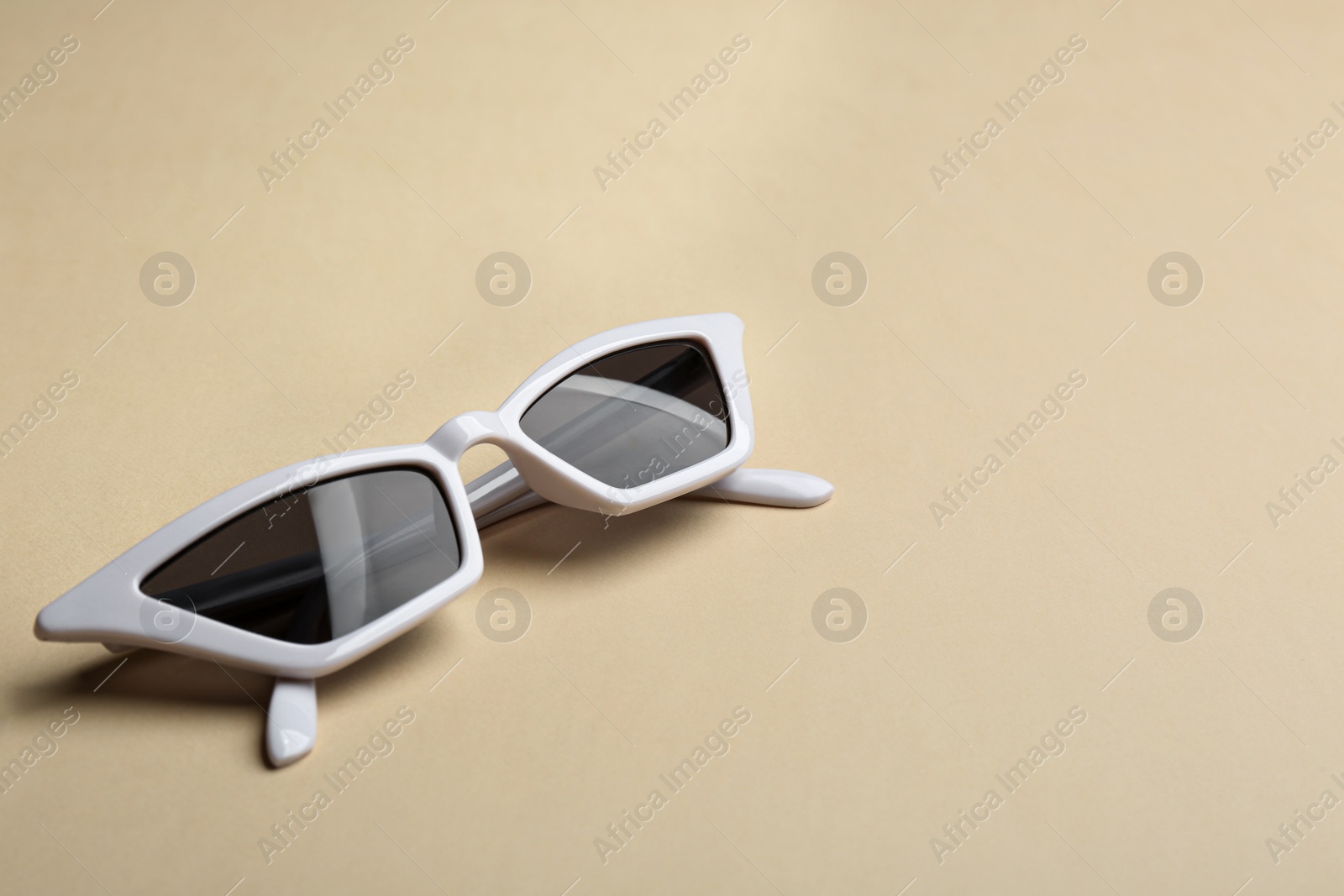 Photo of Stylish sunglasses on beige background, space for text. Fashionable accessory