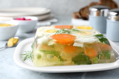 Photo of Delicious fish aspic served on grey marble table, closeup