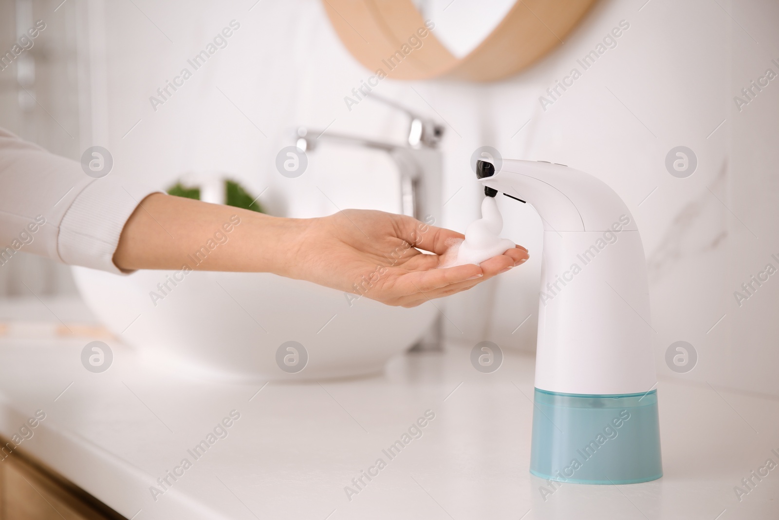 Photo of Woman using automatic soap dispenser in bathroom, closeup