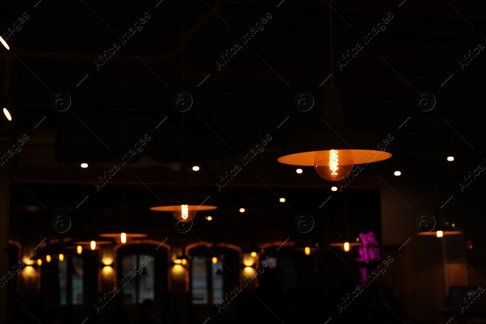 Photo of Lamps with glowing light bulbs in dark restaurant. Space for text