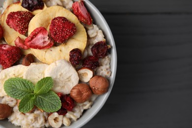 Photo of Oatmeal with freeze dried fruits, nuts and mint on grey wooden table, top view. Space for text