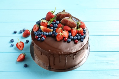 Photo of Fresh delicious homemade chocolate cake with berries on wooden table