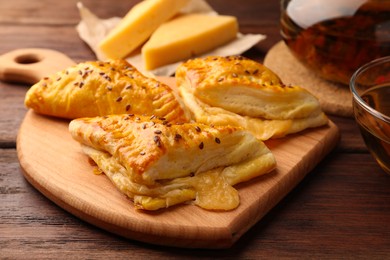 Photo of Fresh delicious puff pastry with cheese on wooden table, closeup