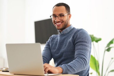 African American man in glasses working on laptop indoors