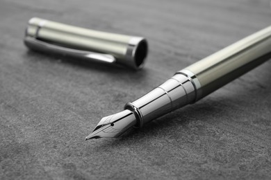 Photo of Stylish silver fountain pen on grey textured table, closeup