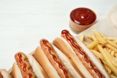 Photo of Hot dogs, french fries and sauce on table, closeup