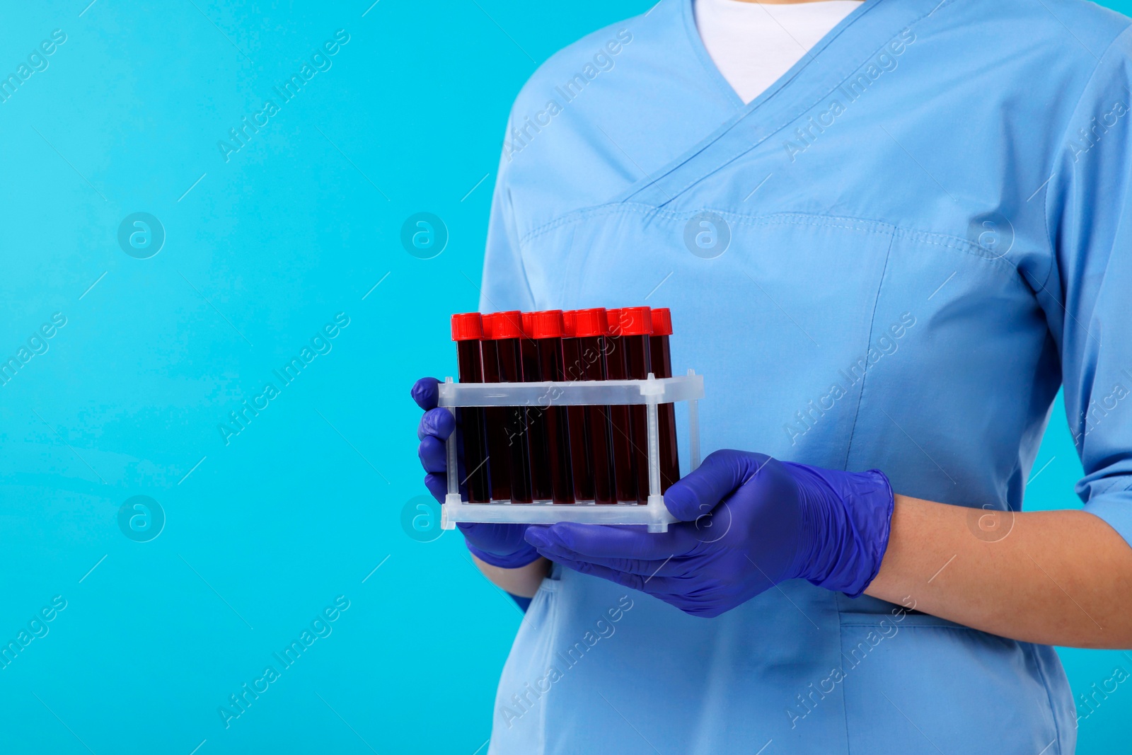 Photo of Laboratory testing. Doctor with blood samples in tubes on light blue background, closeup. Space for text