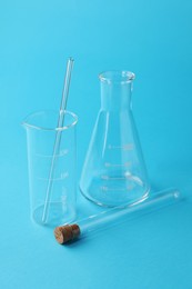Photo of Different laboratory glassware on light blue background