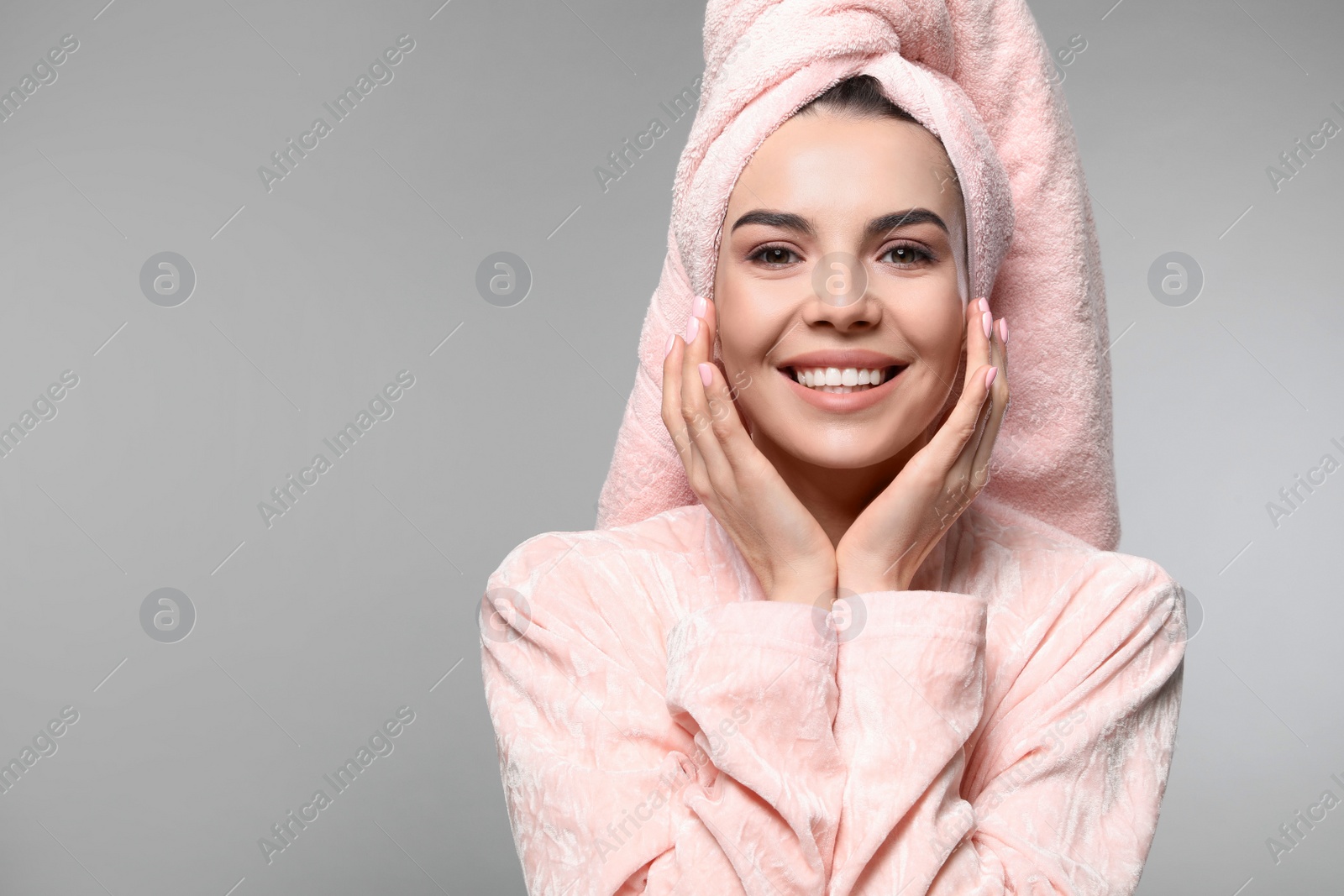 Photo of Happy young woman in bathrobe with towel on head against light grey background, space for text. Washing hair