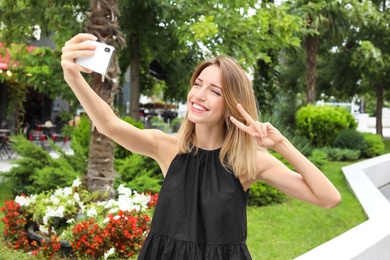 Photo of Attractive woman taking selfie in green park