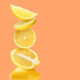 Stacked cut and whole lemons on orange background, space for text